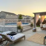 Coastal-inspired above ground pool with white wash wood deck, blue and white decor, and modern backyard pool landscaping