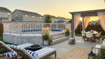 Coastal-inspired above ground pool with white wash wood deck, blue and white decor, and modern backyard pool landscaping