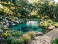 Lush backyard natural pool ideas featuring a rock waterfall, flagstone path, and aquatic plants for an eco-friendly swimming pond.