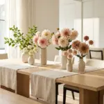 A collection of luxurious dahlia flower arrangements styled on a modern dining room table in bright morning light.
