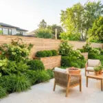 Beautifully landscaped wooden backyard fence with lush green plants, modern garden border, and outdoor living decor ideas.
