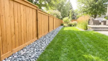 A beautiful wood privacy fence protected by a clean border of crushed landscaping rocks to prevent rot and trimmer damage.