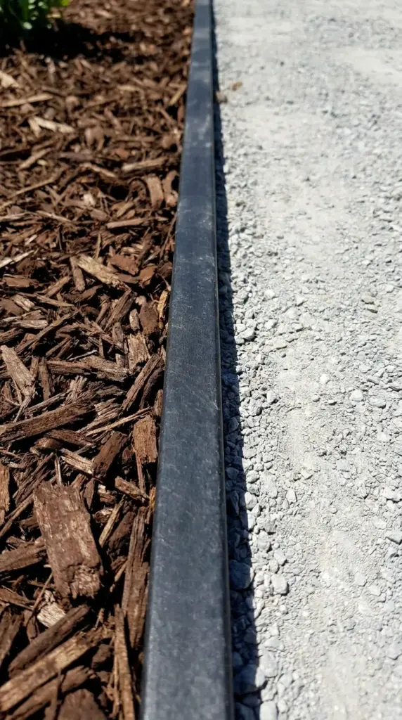 Clean diy garden edging separating dark mulch from light gravel in a front yard.