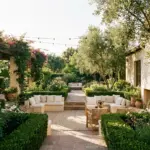 A spacious roofless patio design featuring modern outdoor seating and lush backyard greenery under an open sky.
