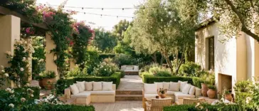 A spacious roofless patio design featuring modern outdoor seating and lush backyard greenery under an open sky.